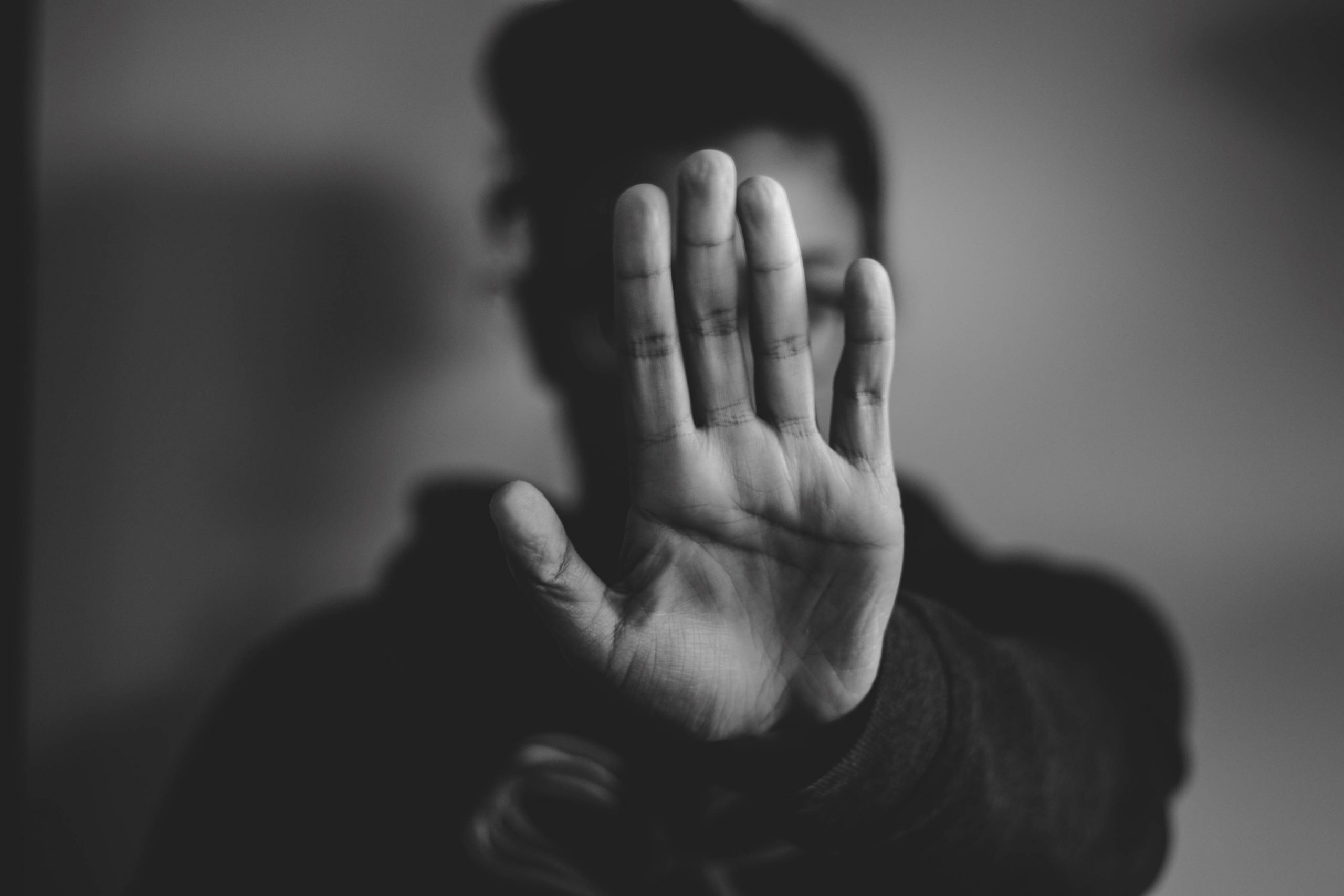 Black and white photo a woman hold up her hand in a 'stop' gesture. Photo by Nadine Shaabana on Unsplash.com