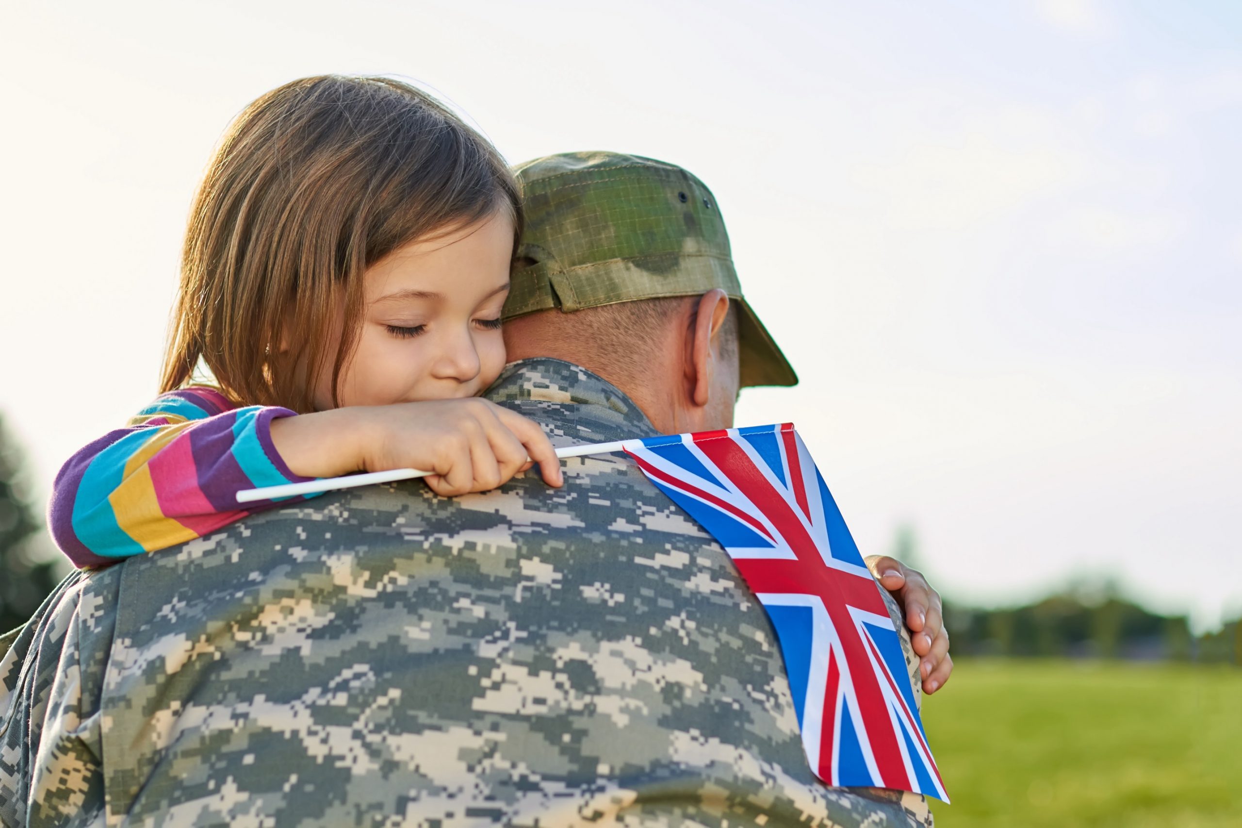 Happy reunion of british soldier and his little daughter. Girl with british flag is embracing her father. Photo by DenisProduction.com on Shutterstock